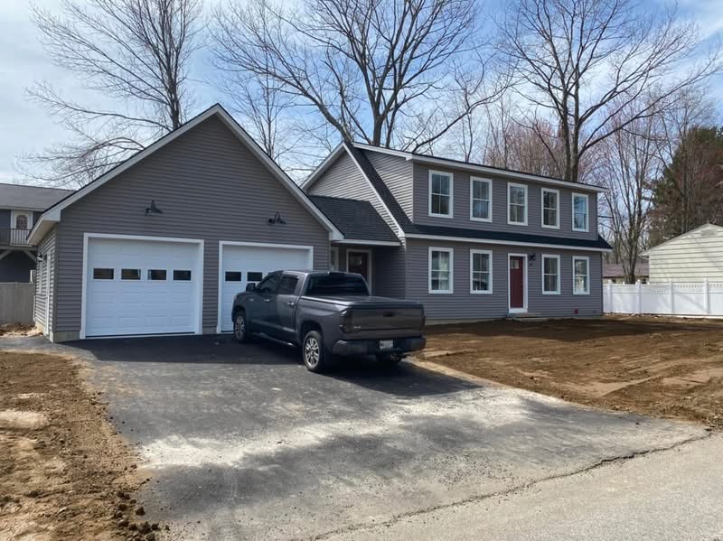 Gray colonial home with attached two-car garage and paved driveway