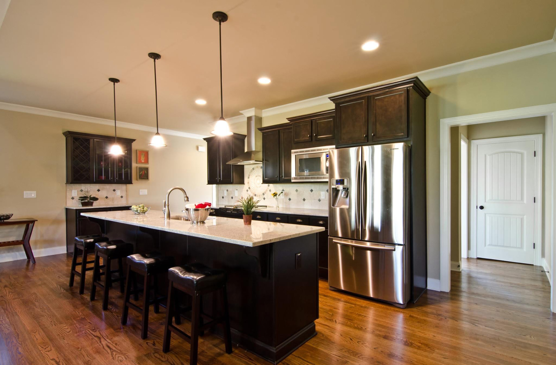Custom kitchen with espresso cabinetry, granite island seating, and hardwood floors