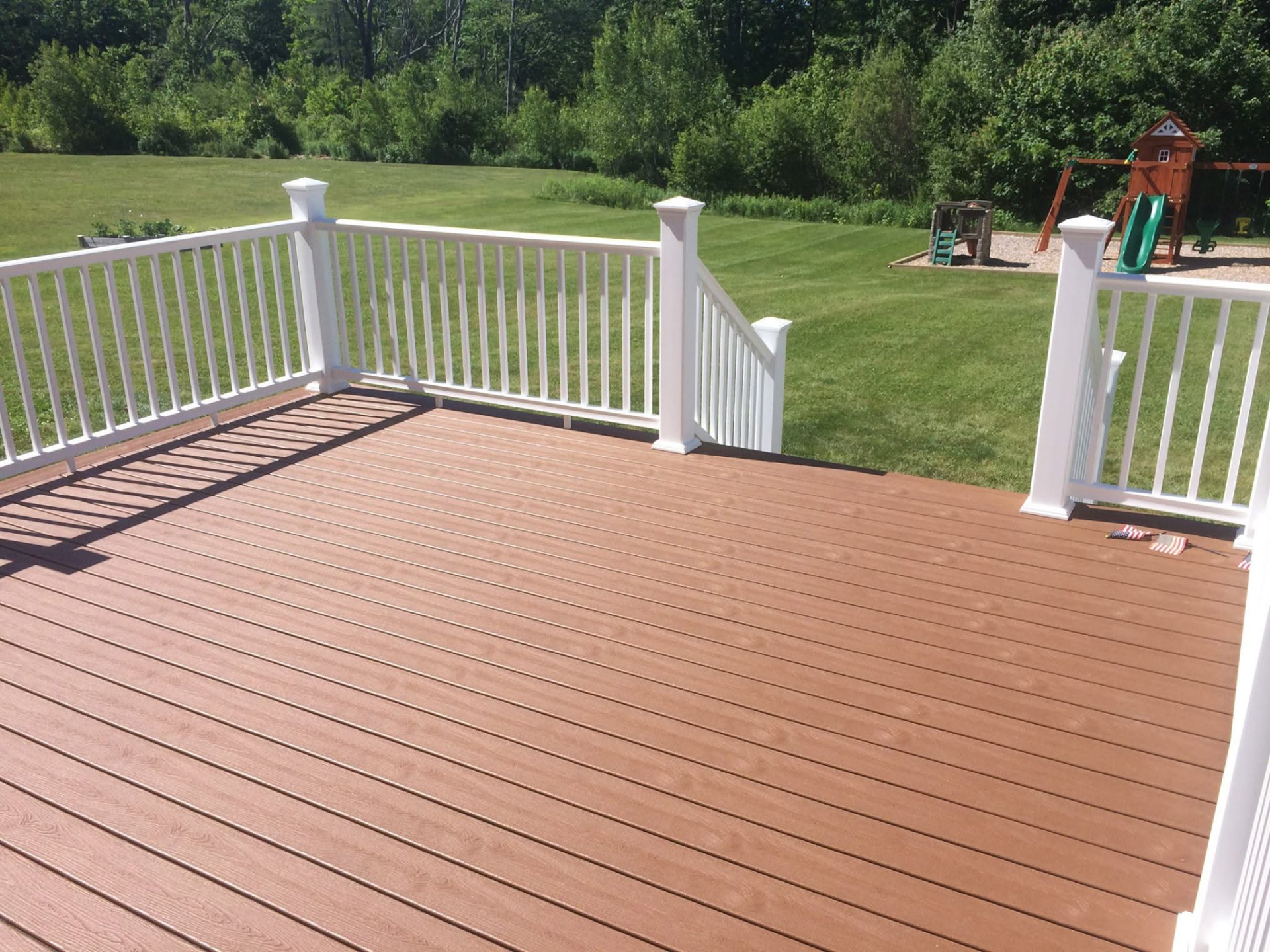 Composite deck with white vinyl railing overlooking a Maine backyard