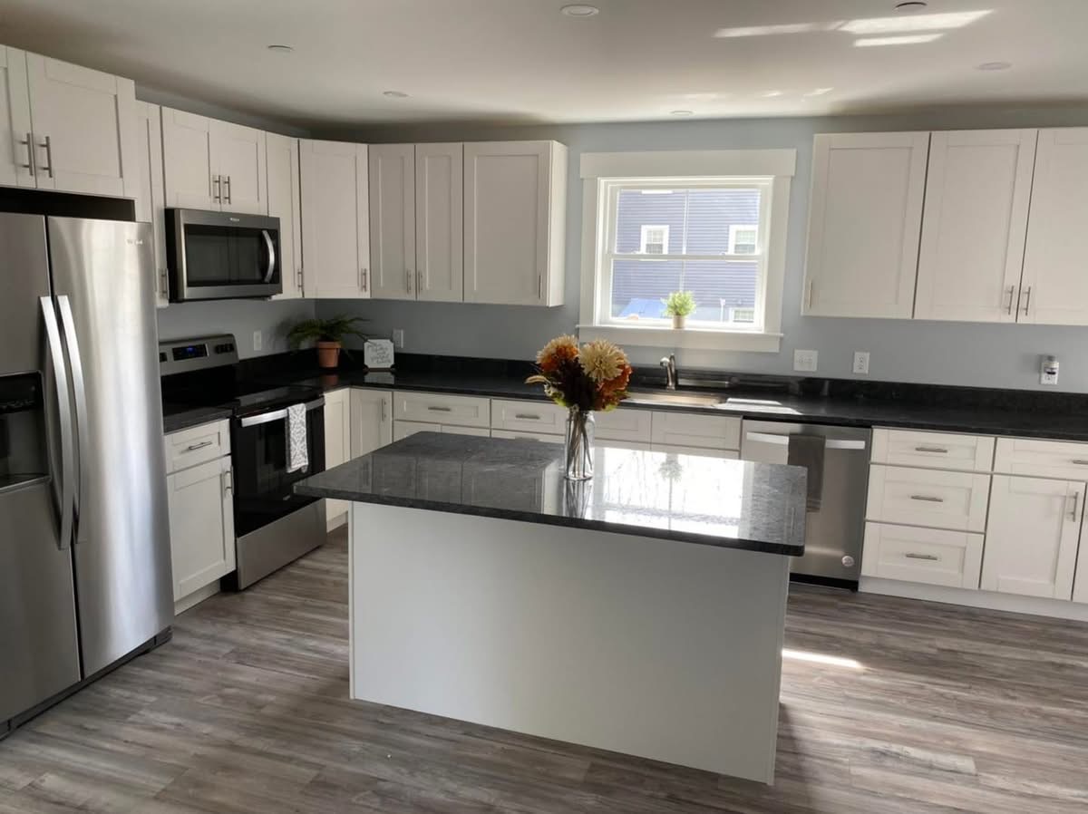 Remodeled kitchen with white shaker cabinets, dark granite counters, and stainless appliances