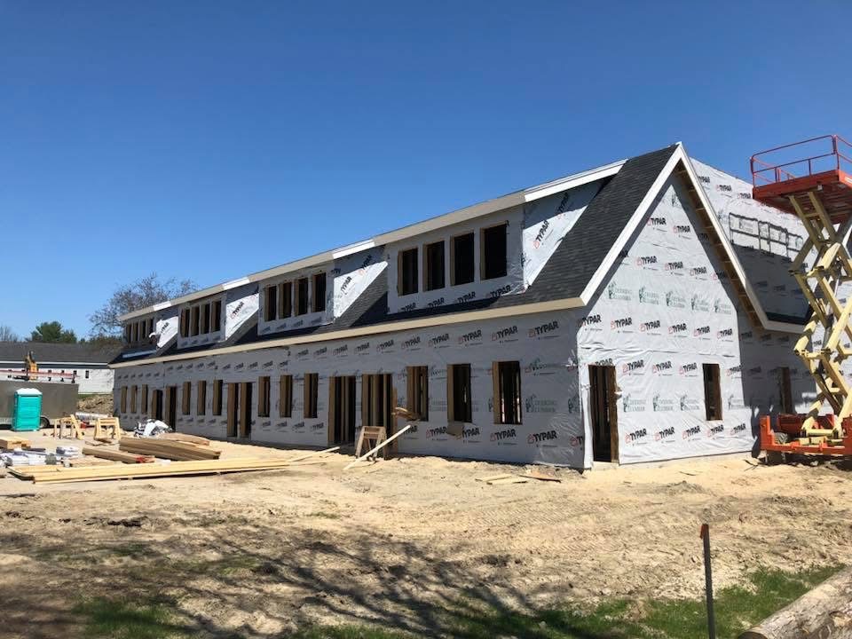 Large multi-unit building under construction with house wrap and dormers