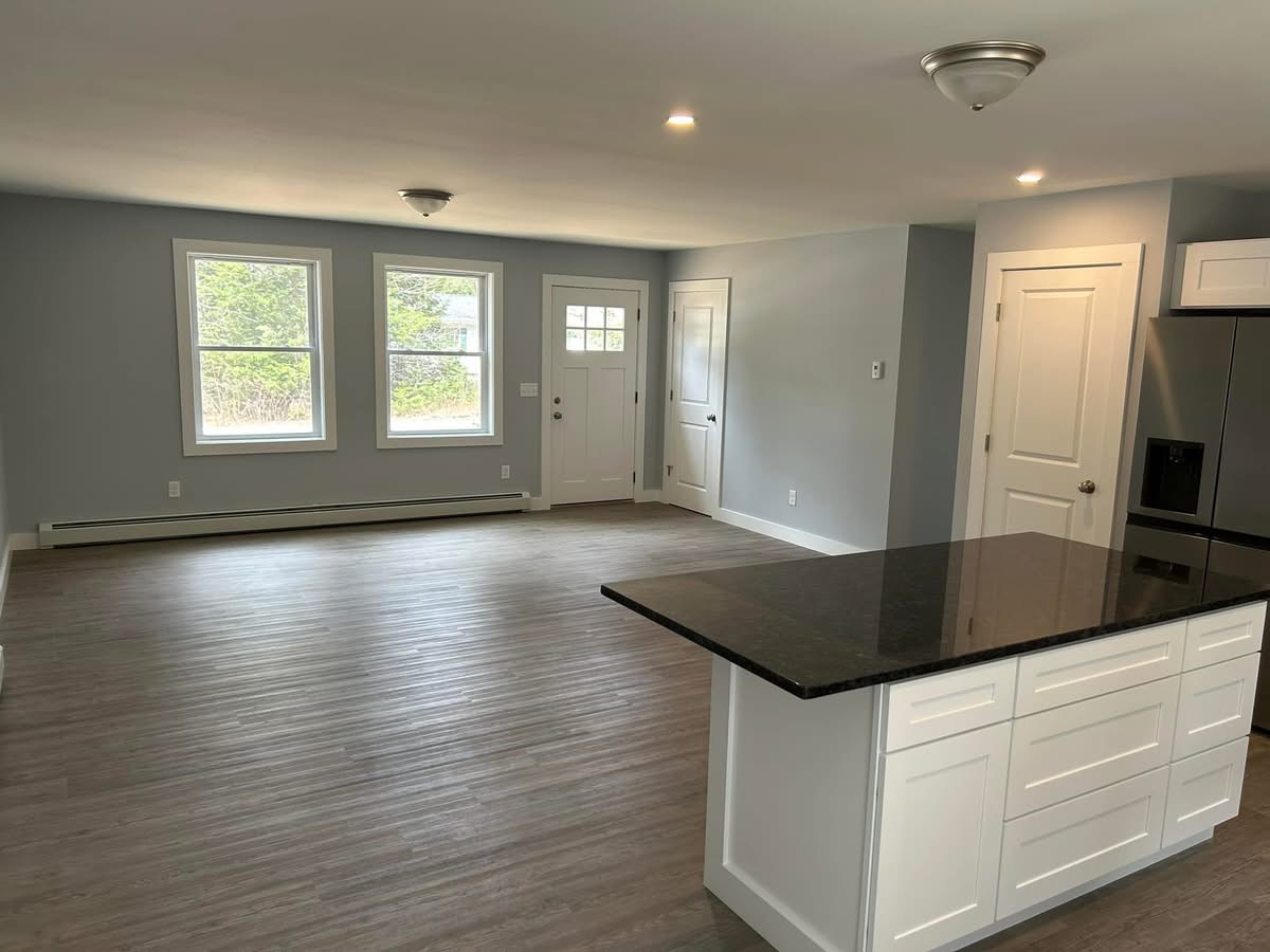 Open living space with gray walls, vinyl plank flooring, and a granite-topped kitchen island