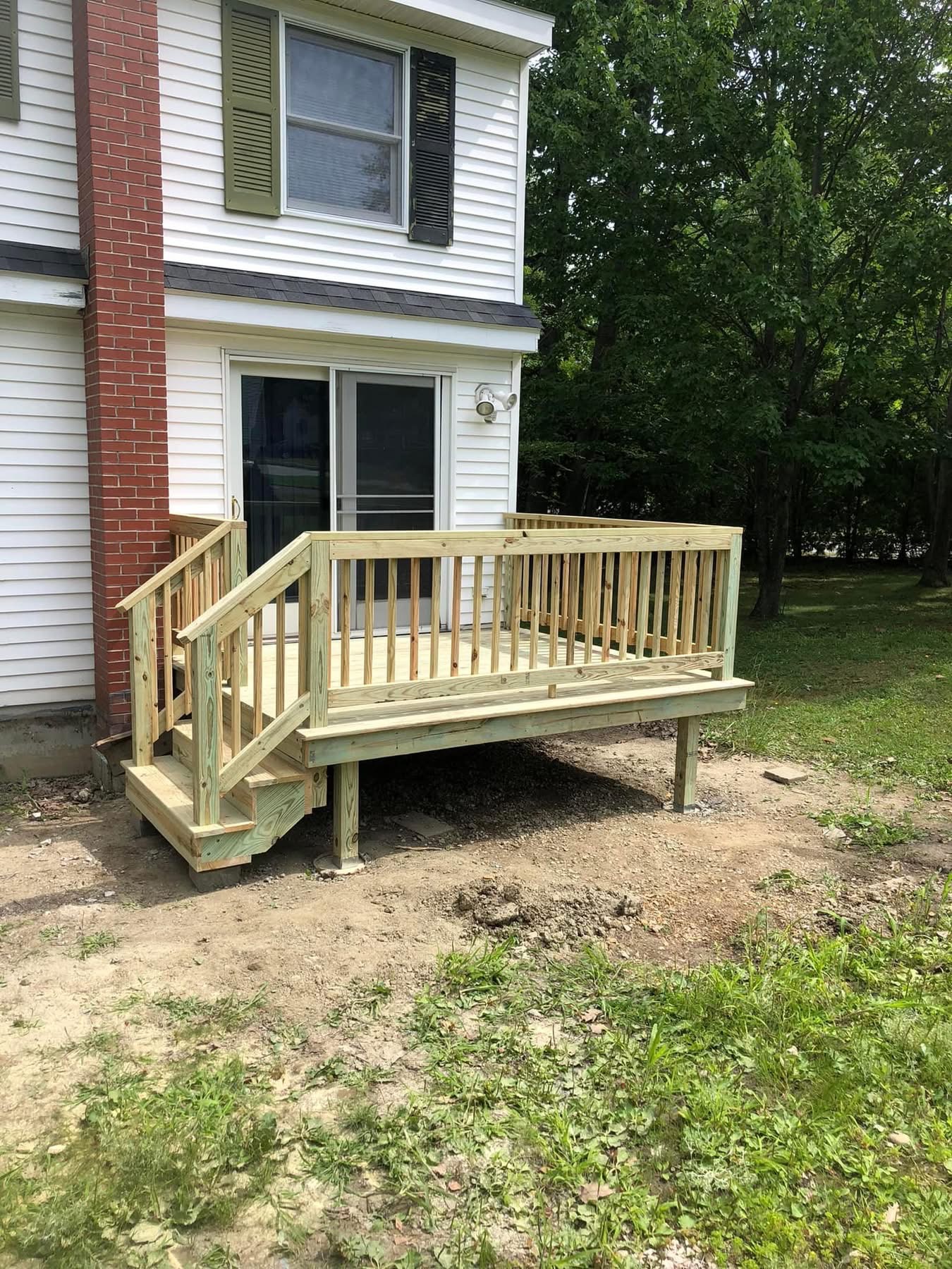 New pressure-treated deck with railing and stairs off a sliding door