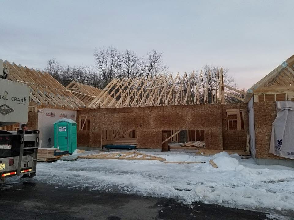 New home framing with roof trusses set by crane on a winter jobsite