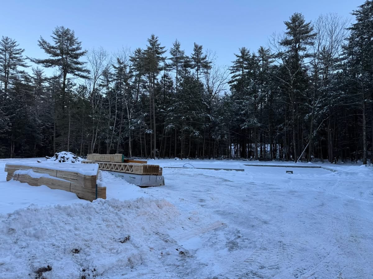 Winter jobsite with foundation poured and floor trusses staged for framing