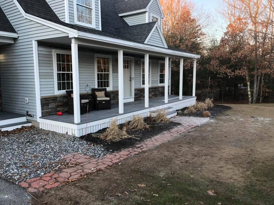 Farmer's porch with stone accents and columns on a Maine home