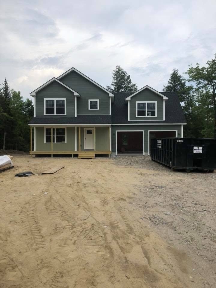 Newly built green two-story home with farmer's porch and attached garage