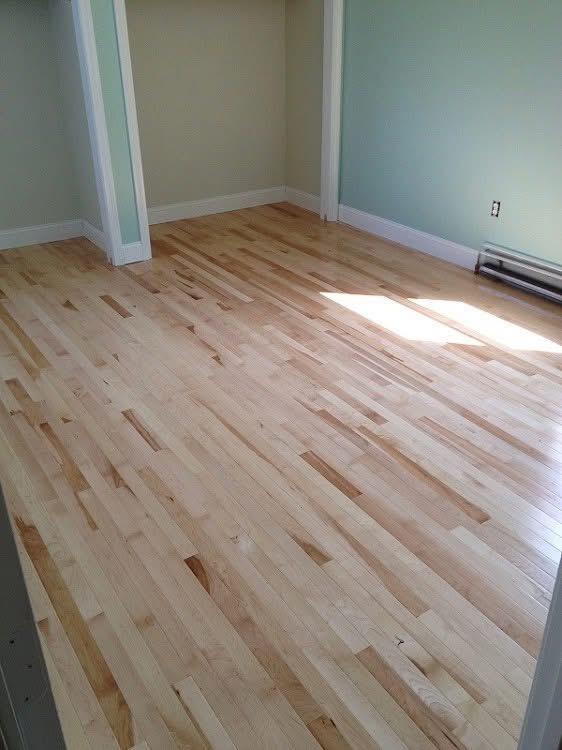 Freshly installed maple hardwood flooring in a remodeled bedroom