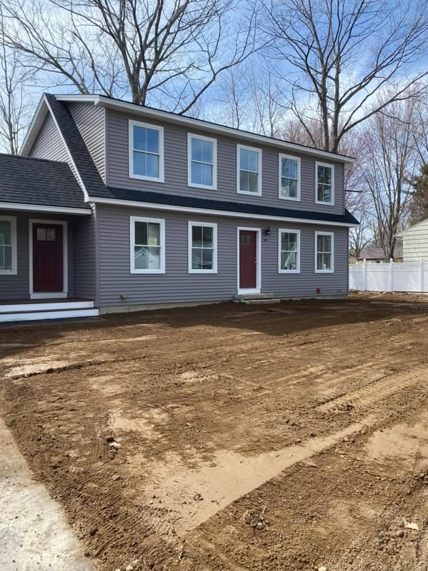 Newly built gray colonial home with white trim and red front doors