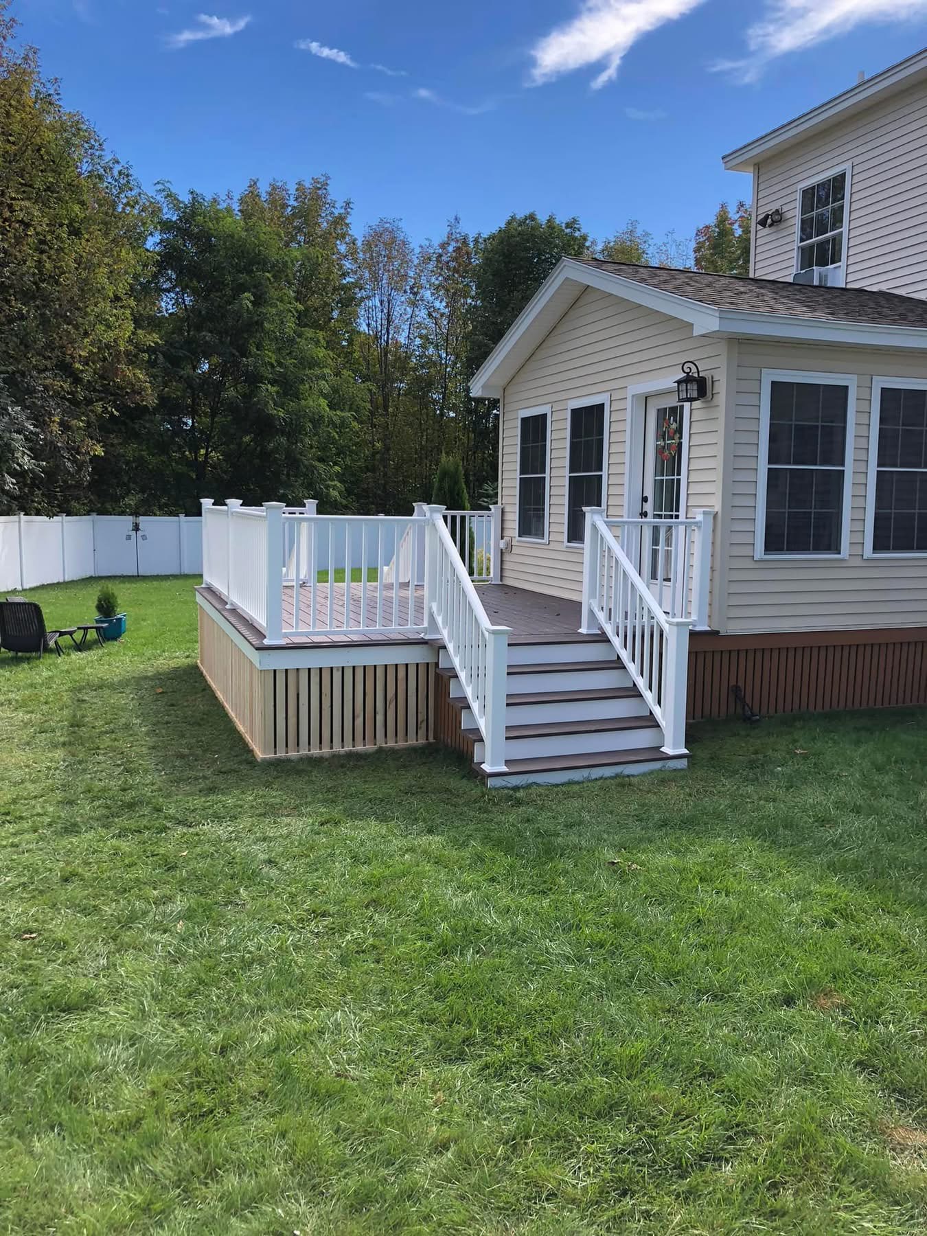 Composite deck with white vinyl railing and stairs off a sunroom addition