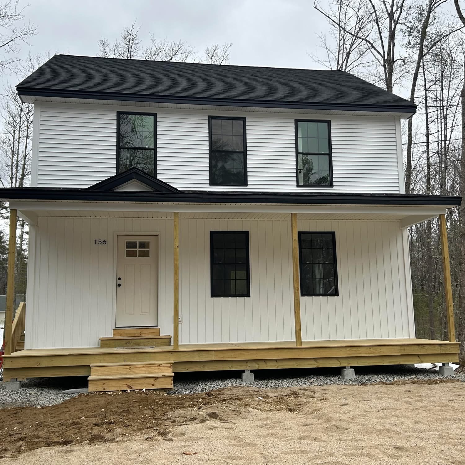 Two-story white farmhouse-style home with a large covered porch built by JT Construction of Maine