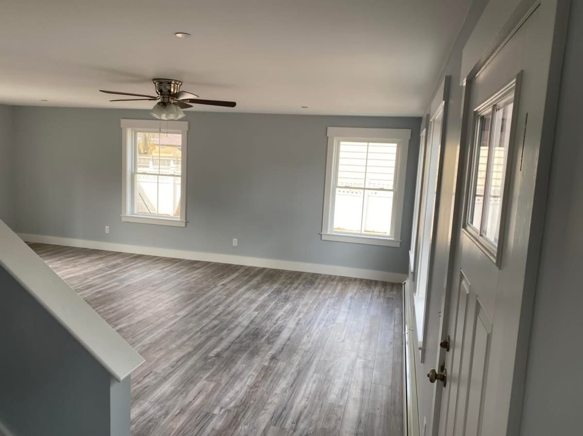 Remodeled second-floor living area with ceiling fan and new plank flooring