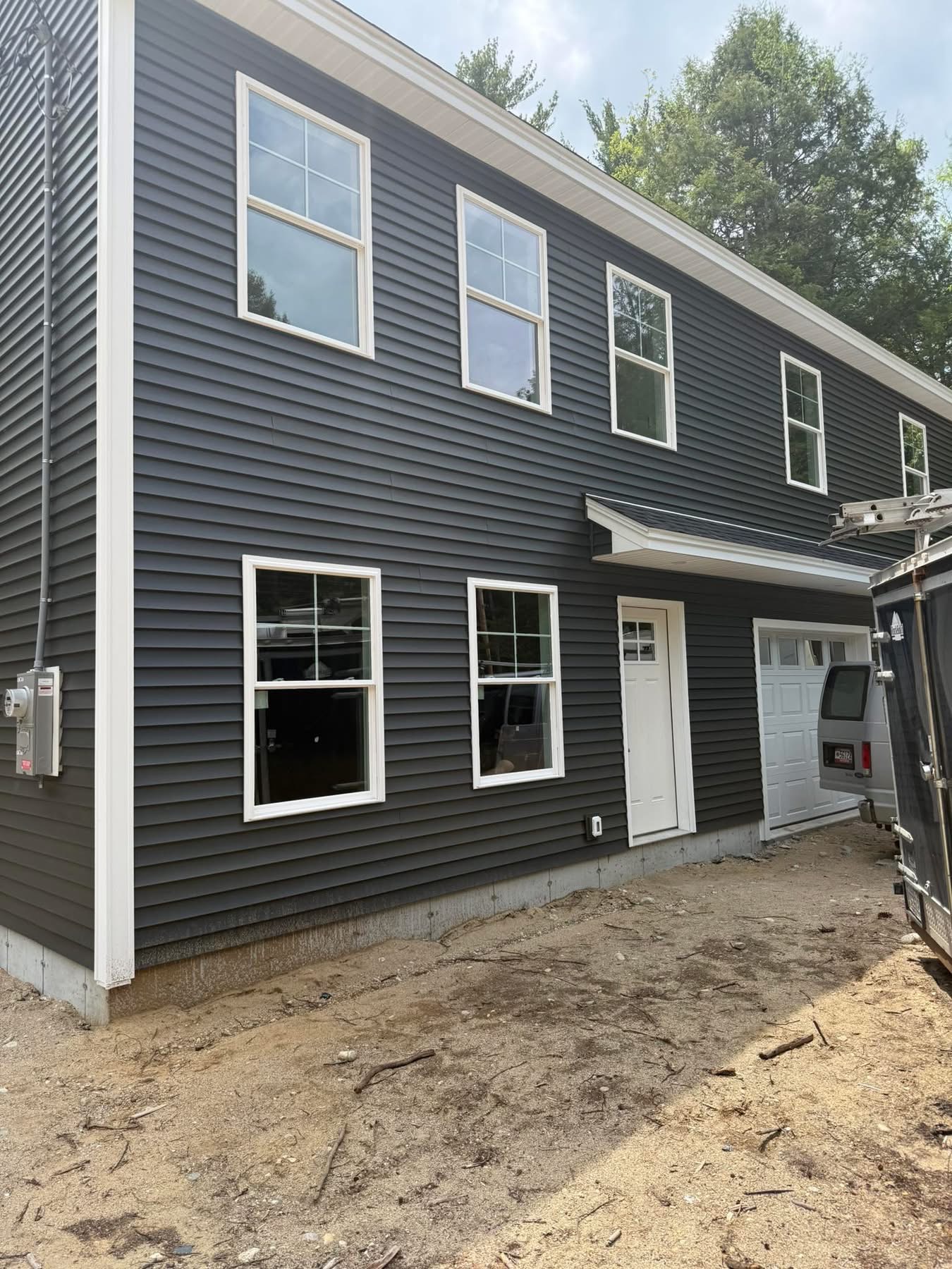 New home with dark gray vinyl siding, white trim, and attached garage