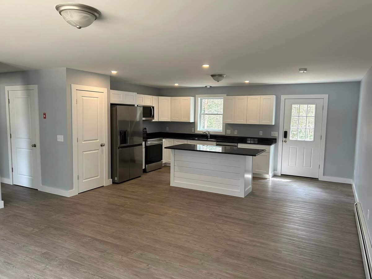 Open-concept kitchen with white cabinetry, granite island, and stainless appliances