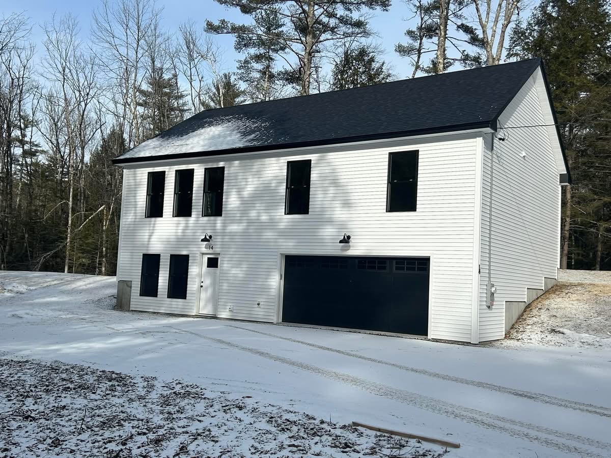 White two-story garage with living space and black carriage-style overhead door