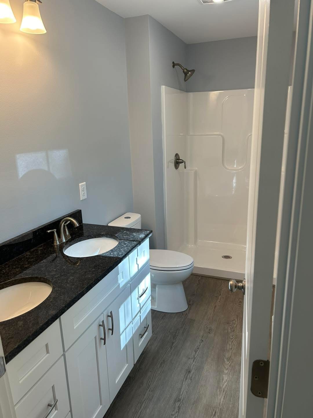 New bathroom with double granite vanity and fiberglass shower